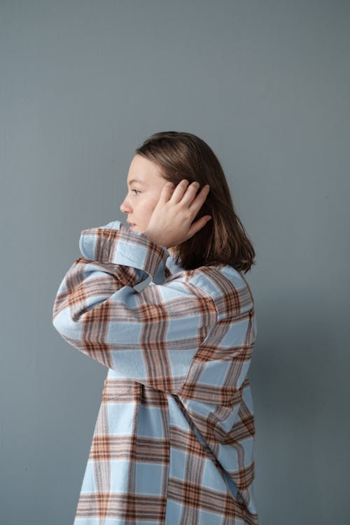 Photo of a Woman in a Plaid Shirt Fixing Her Hair