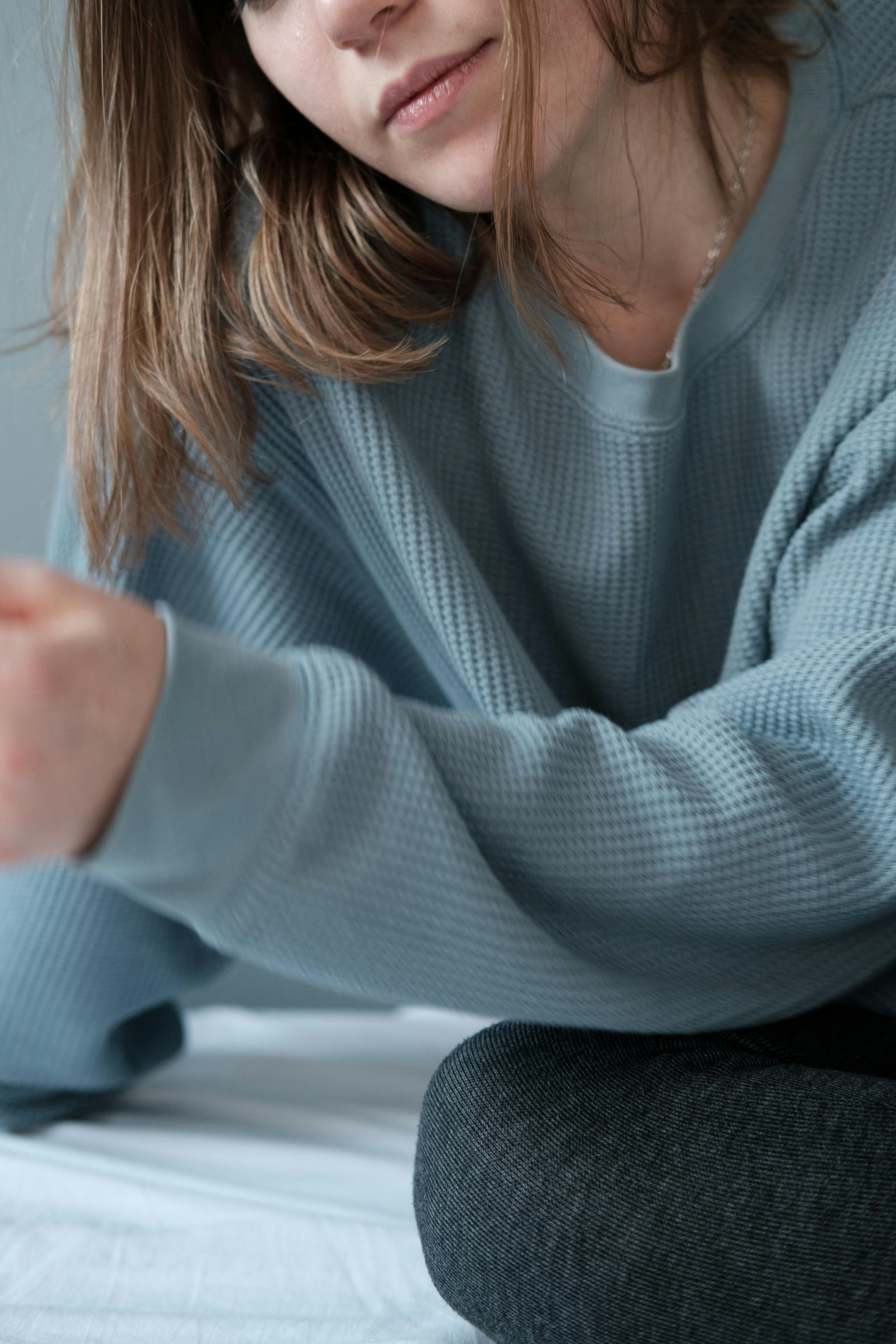 Close-up of a woman wearing a blue sweater, sitting comfortably indoors.