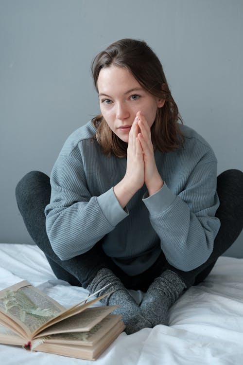 Free Woman in Gray Sweater Sitting on Bed Stock Photo