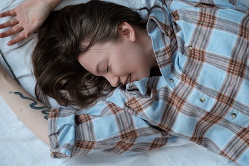 Free Girl in Blue White and Red Plaid Dress Shirt Lying on Bed Stock Photo