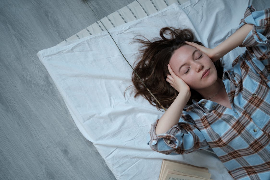 Free Girl in Blue White and Red Plaid Shirt Lying on Bed Stock Photo