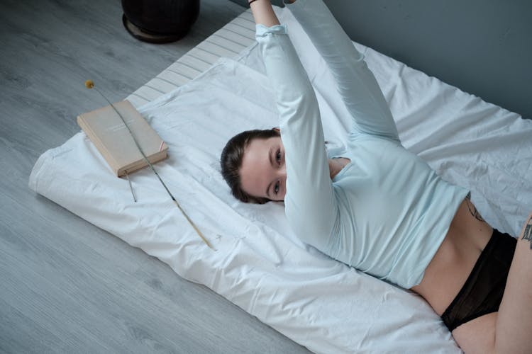 A Woman In White Long Sleeve Shirt And Black Panty Lying On Bed