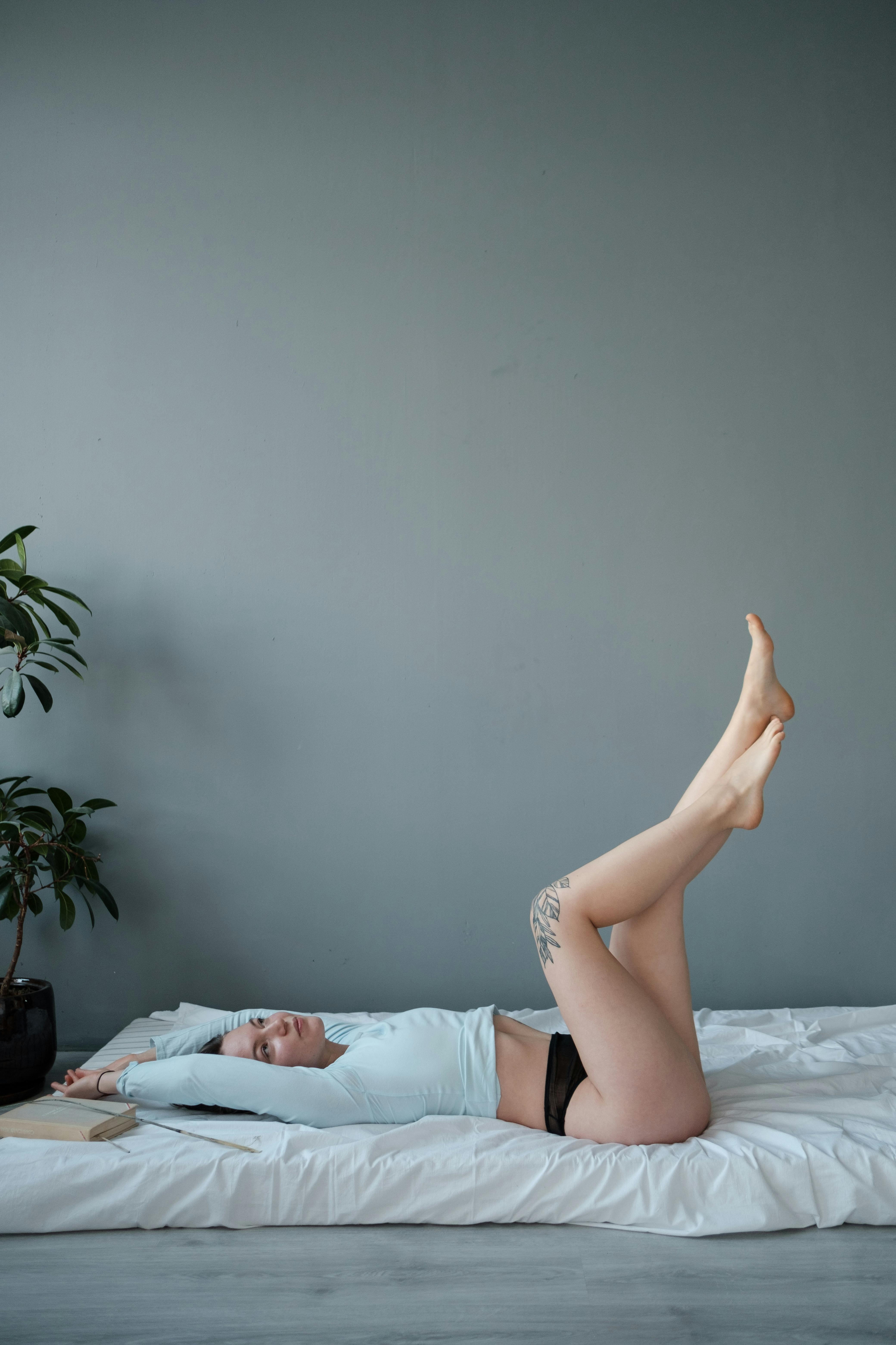 Woman relaxing indoors on bed, with peaceful posture and calm atmosphere.