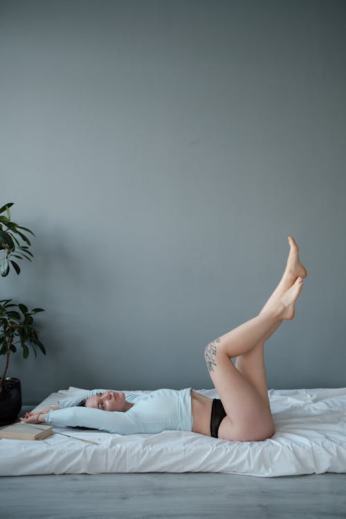 Free Relaxed woman lying on mattress with legs raised Stock Photo