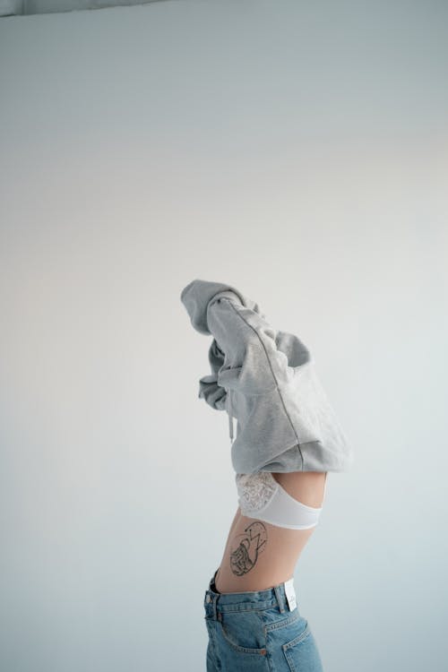 Woman in panties taking off black sweatshirt · Free Stock Photo