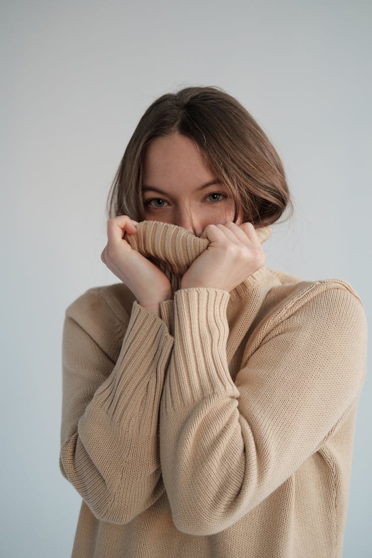 Coquettish Woman Covering Face With Beige Sweater