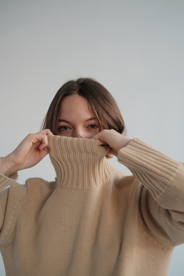 Woman Covering Face With Turtleneck In Studio