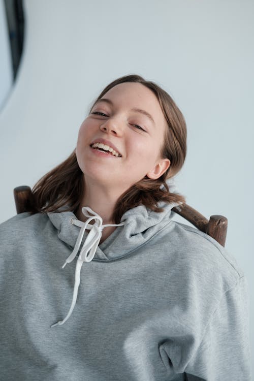 Smiling woman in hoodie sitting on chair in studio