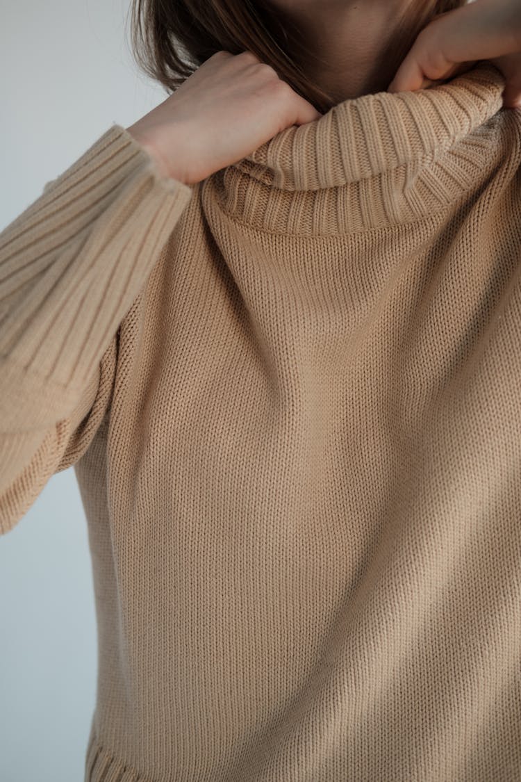 Woman Adjusting Warm Sweater Collar In Studio