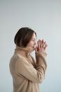 Melancholic female in sweater standing with hands together