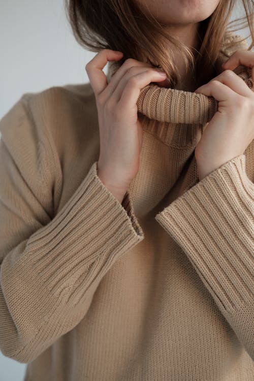 Free Crop unrecognizable female with long hair wearing soft warm sweater with long collar Stock Photo