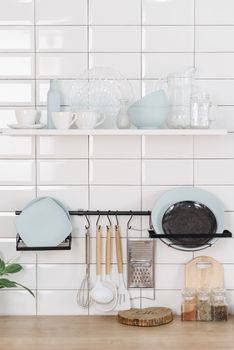 Neatly arranged kitchen items on a white tiled wall, showcasing simplicity and style.