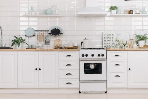 White Wooden Kitchen Cabinets With Dishware and Stove