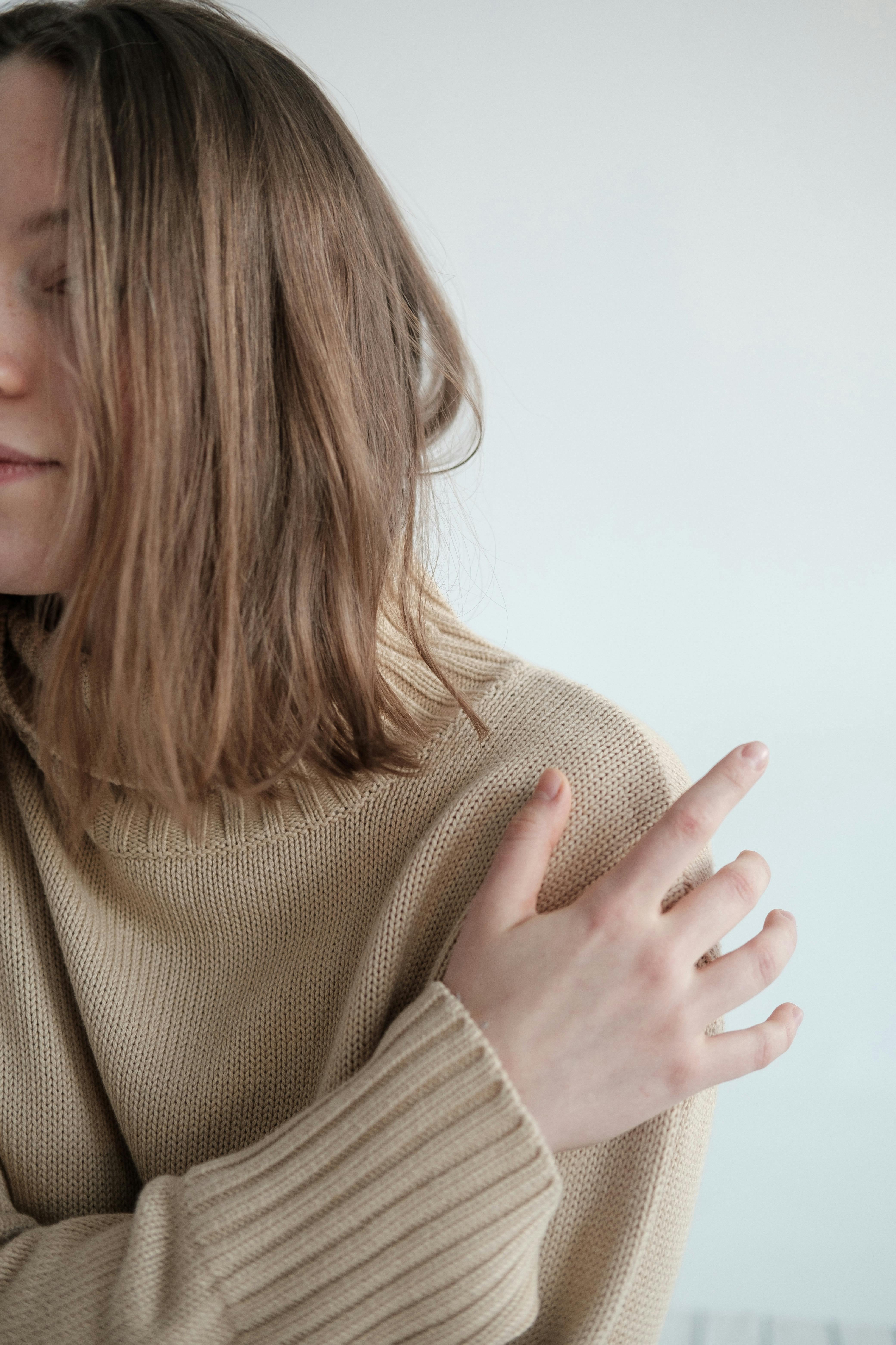 young woman in warm sweater hugging herself