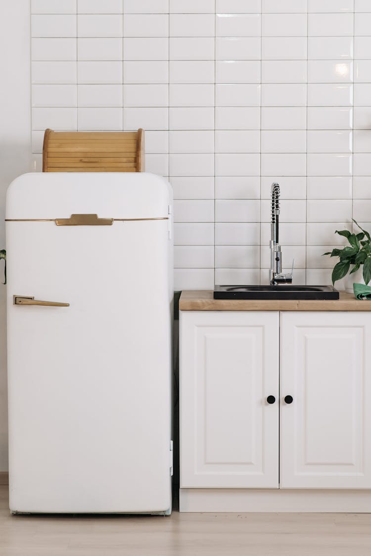 White Fridge Beside Kitchen Cabinet With Sink