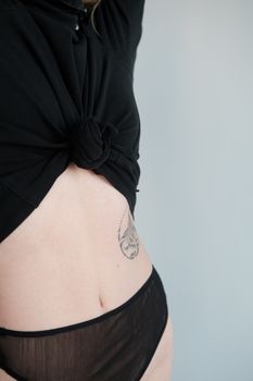 Crop unrecognizable female wearing panties and bra standing against gray background in studio