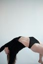 Unrecognizable flexible woman performing bridge exercise on white background