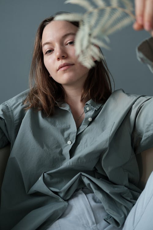 Woman with branch of plant sitting on sofa