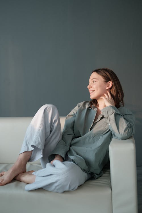 Free Smiling woman sitting on couch with legs crossed Stock Photo