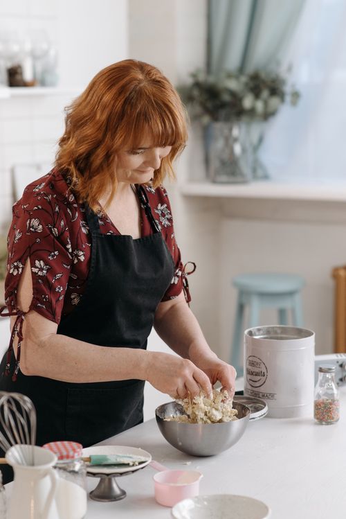 Free Woman wearing apron kneading dough in a homely kitchen environment, perfect for baking and culinary themes. Stock Photo