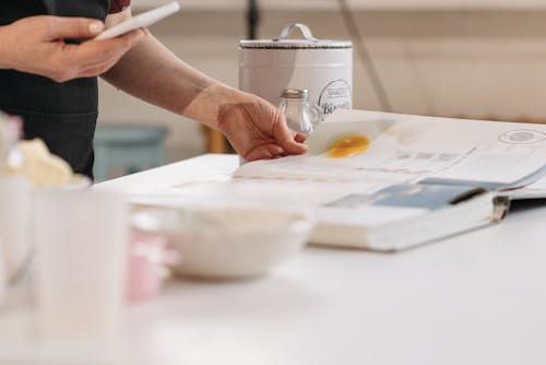 Person Holding Silver Cup Pouring Water on White Ceramic Bowl