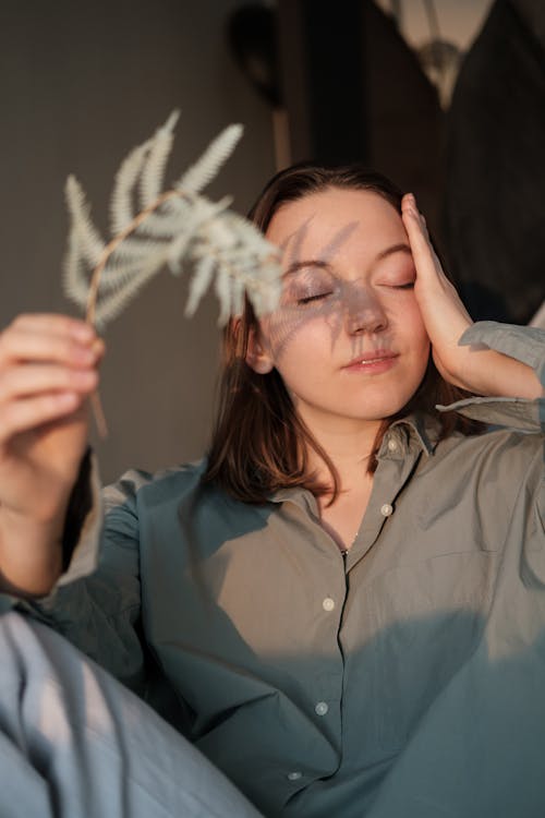 Woman covering face with branch from sunshine