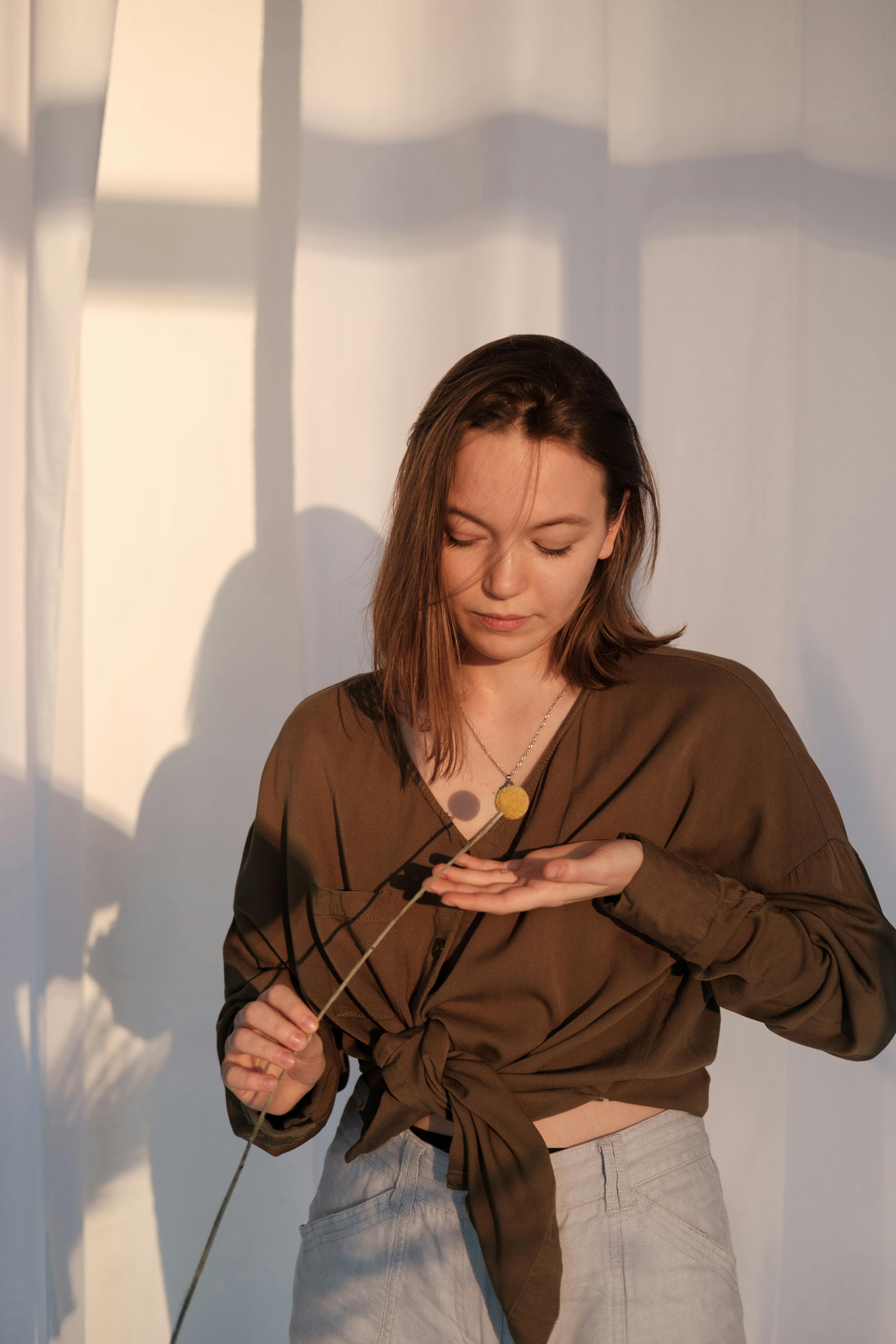 young woman with floral branch standing in sunlight