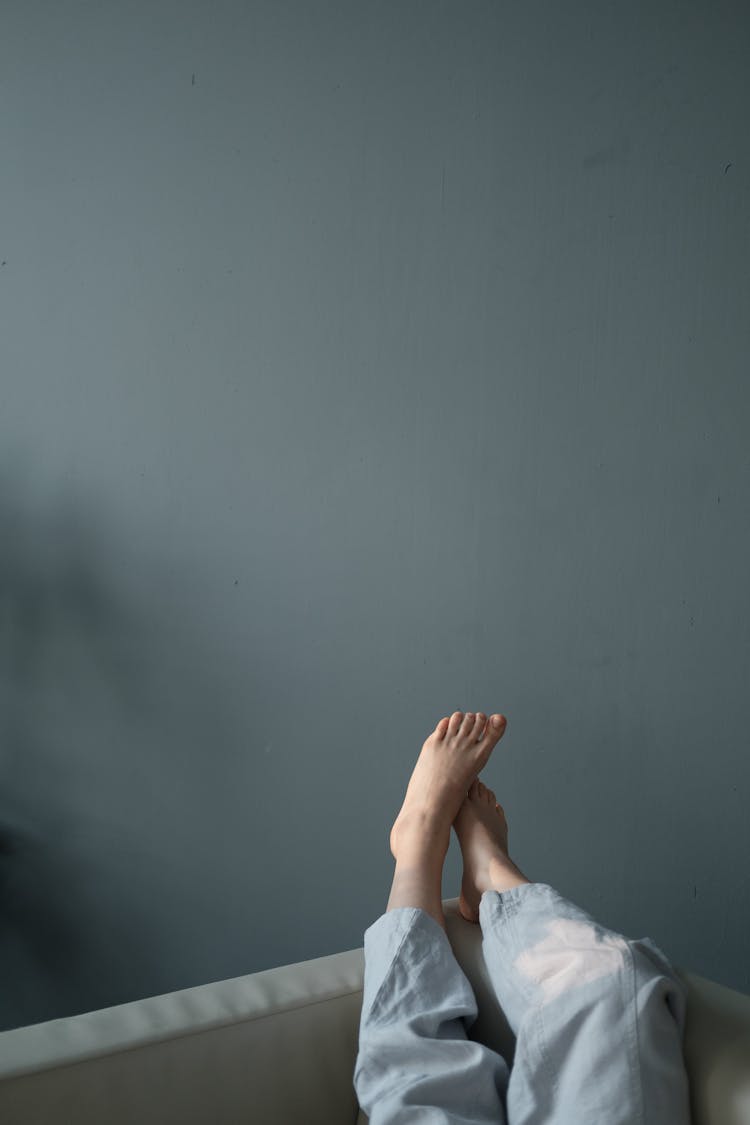 Barefoot Female Lying On Sofa At Home