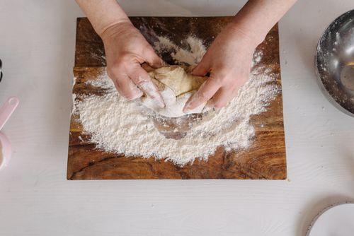 Free Close-up of hands kneading dough with flour on a wooden board for baking. Stock Photo