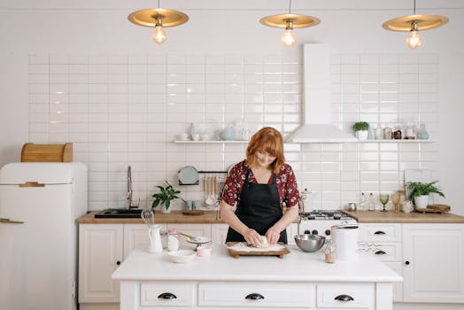 A woman happily kneading dough on a wooden board in a stylish, modern kitchen.