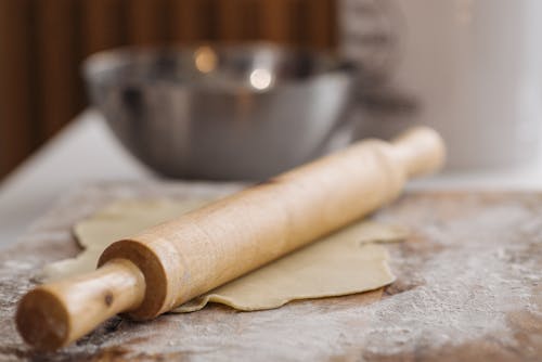 A Close-Up Shot of a Rolling Pin Over a Dough