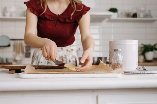 Woman's hands placing cookie dough on parchment paper in a cozy kitchen.