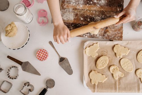 Free Hands rolling dough for cookies with baking tools and ingredients on a wooden table. Stock Photo