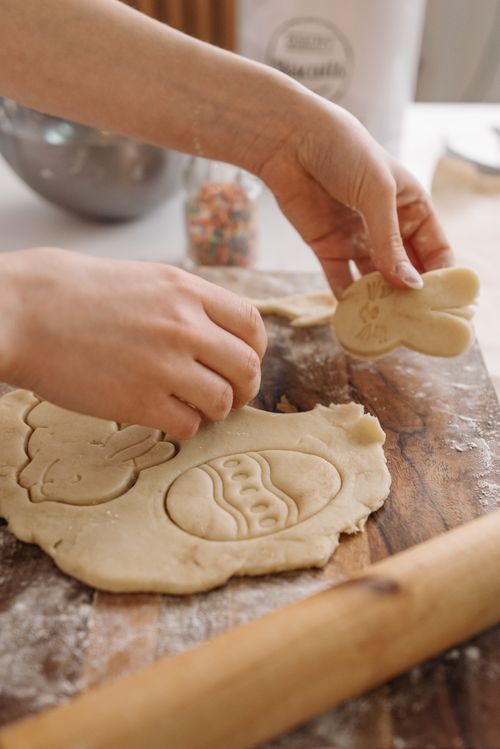 Free Hands cutting Easter-themed cookies from dough on a wooden board. Stock Photo