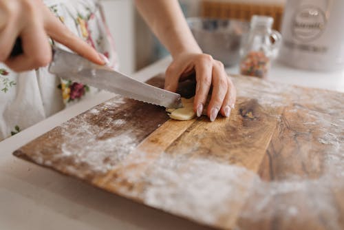 Person Slicing a Dough on the Brown Chopping Board