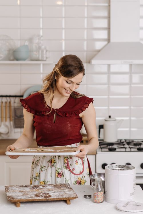 Free Smiling woman in a kitchen prepares homemade cookies, embracing culinary joy. Stock Photo