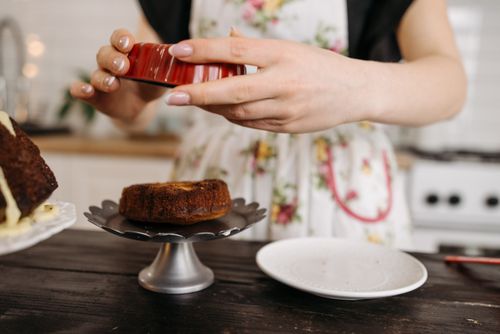 Free Close-up of hands demolding a small cake from a mold onto a cake stand in a cozy kitchen. Stock Photo
