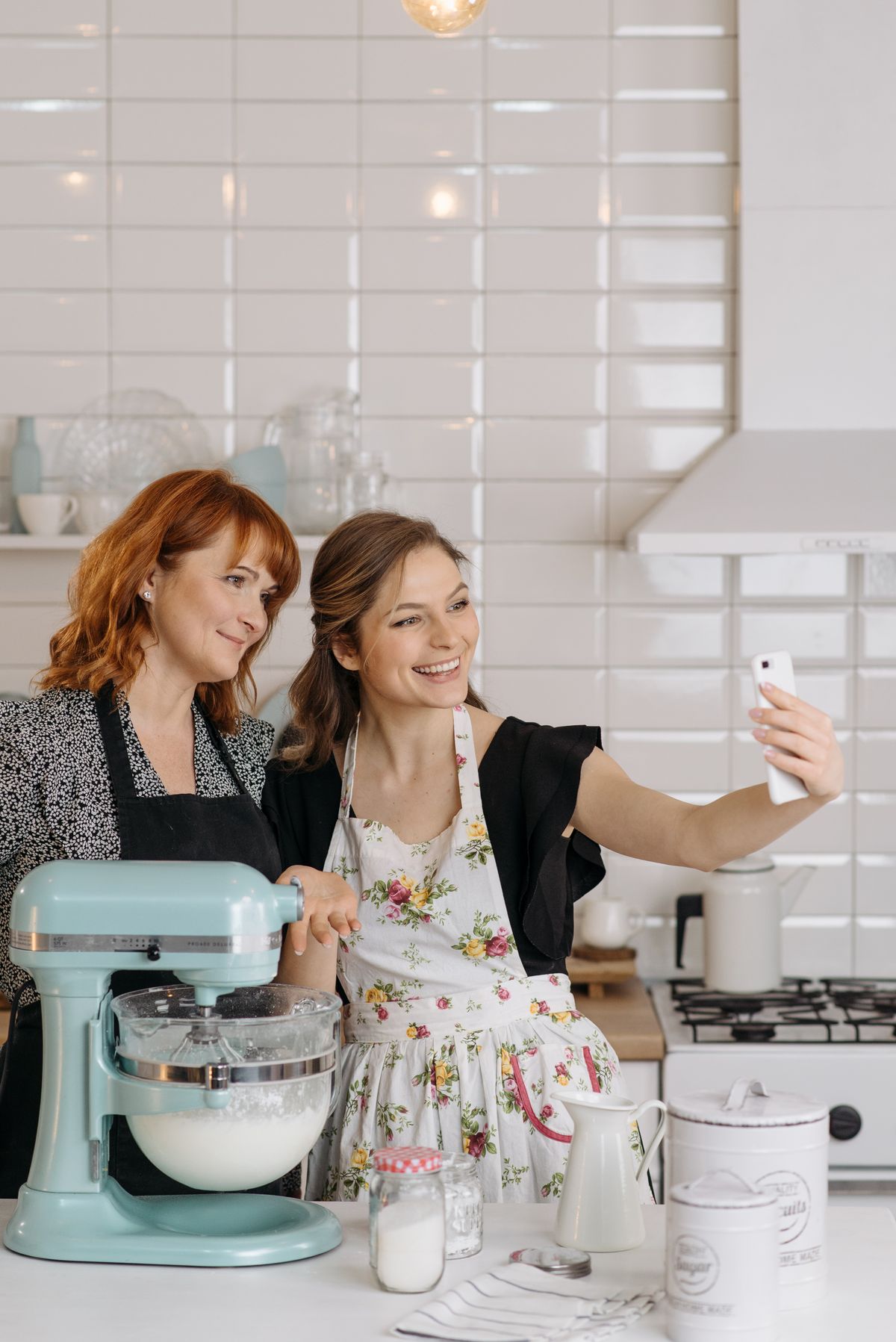 Two women standing in a kitchen taking a selfie together