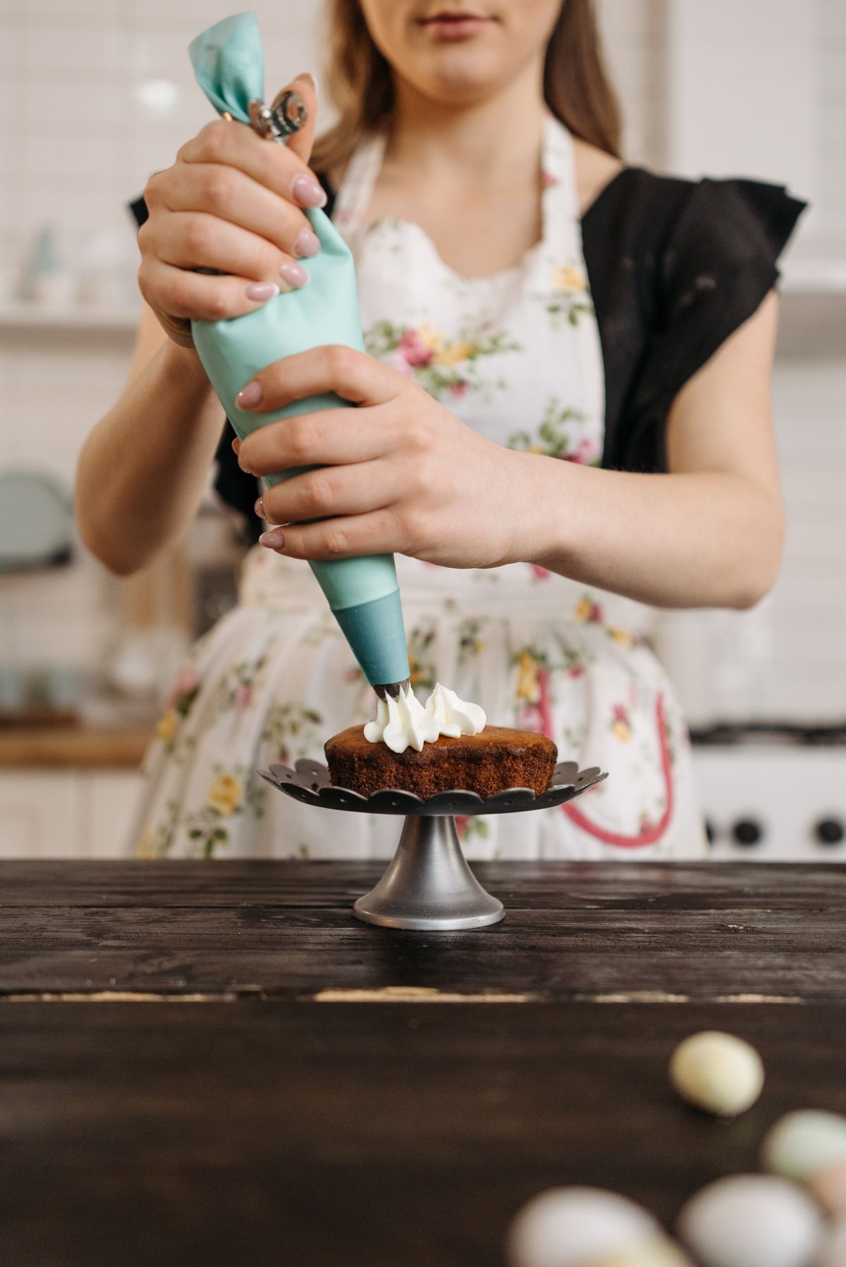 Close-up of hands piping icing onto a cake