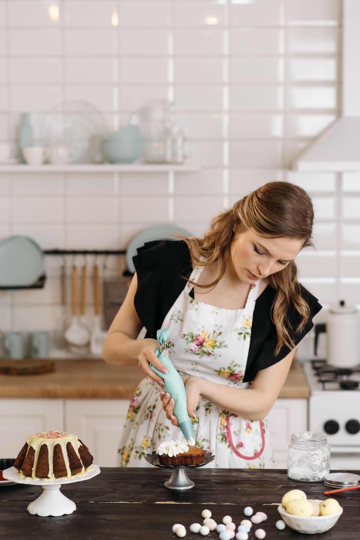 Woman in a floral apron decorating a cake with icing