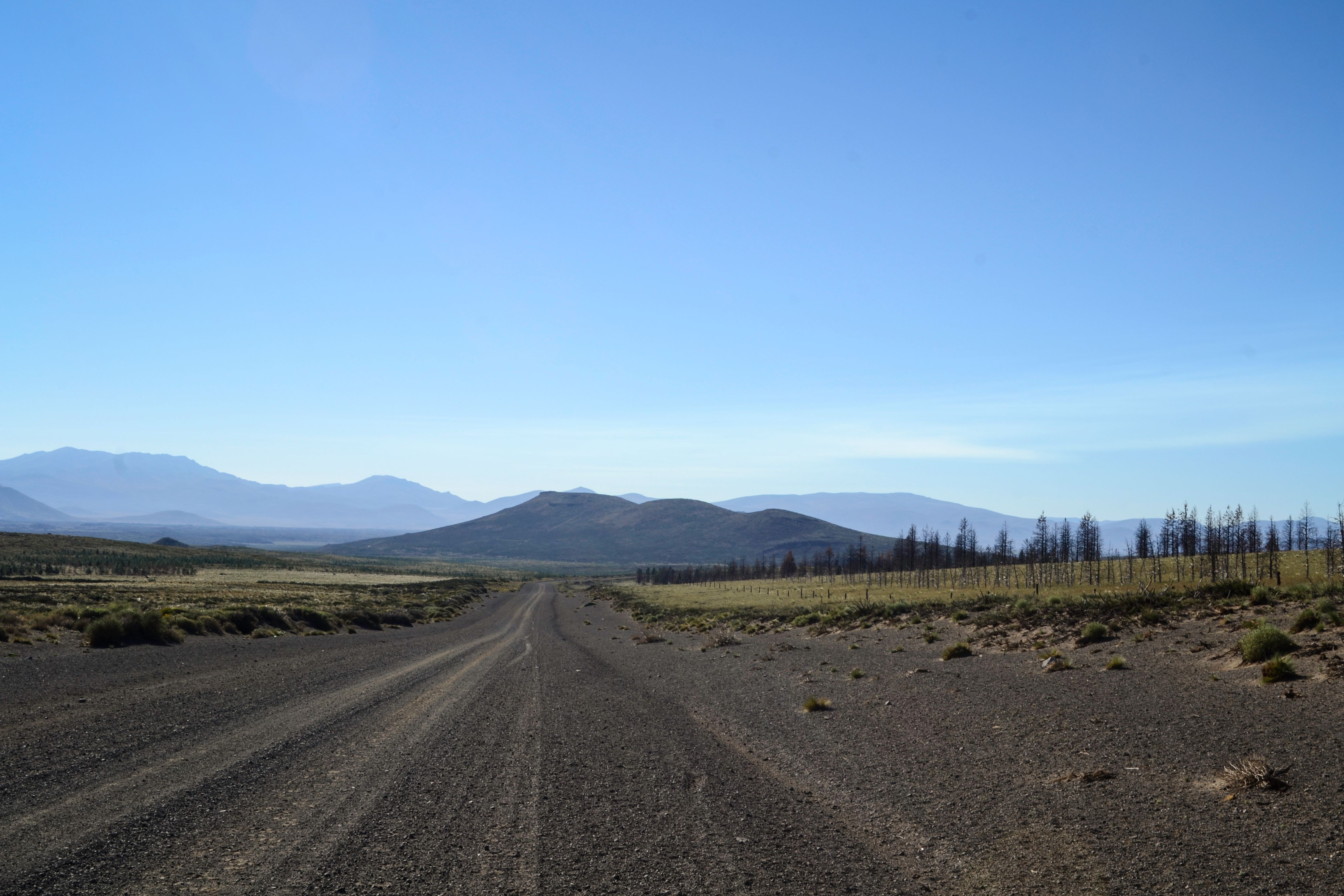 Expansive dirt road in Caviahue, Argentina with a clear blue sky and surrounding mountains.