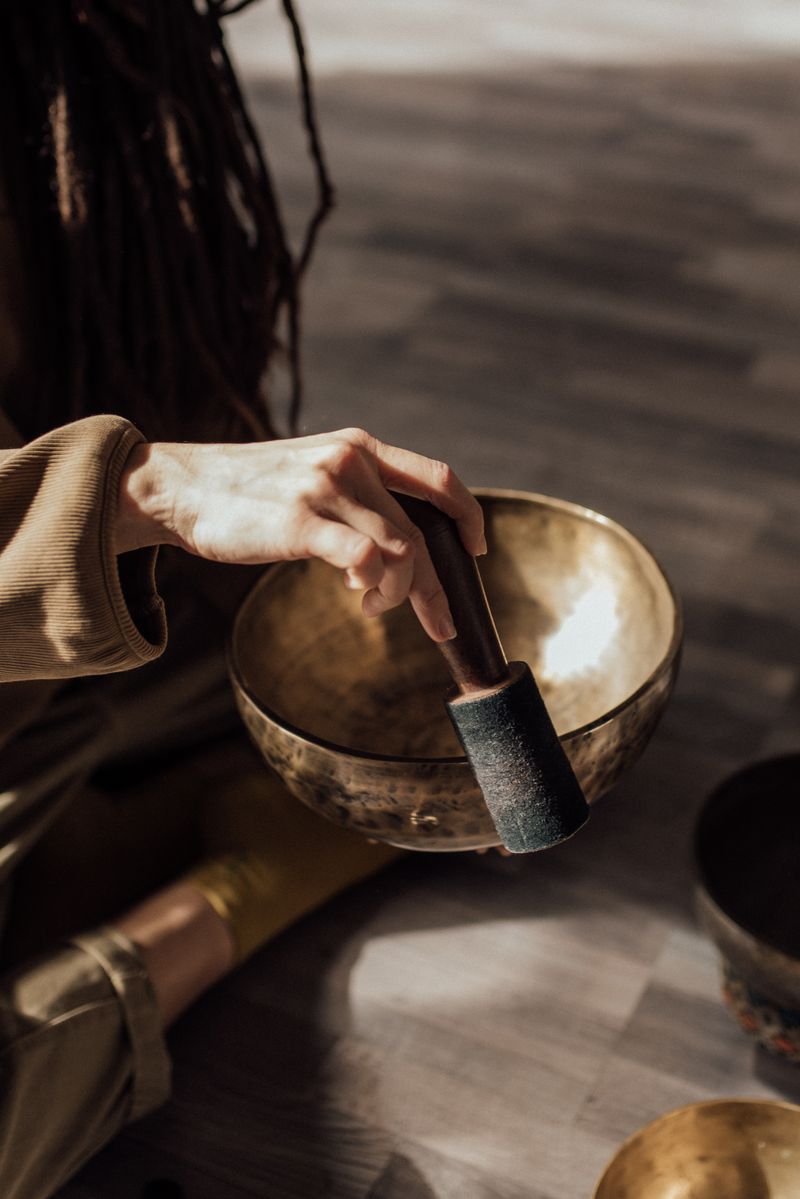 Hand holding a mallet over a Tibetan singing bowl for meditation