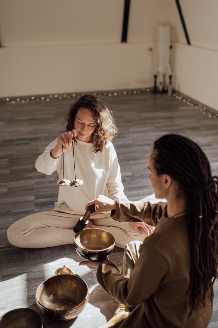 Two women meditating with Tibetan singing bowls