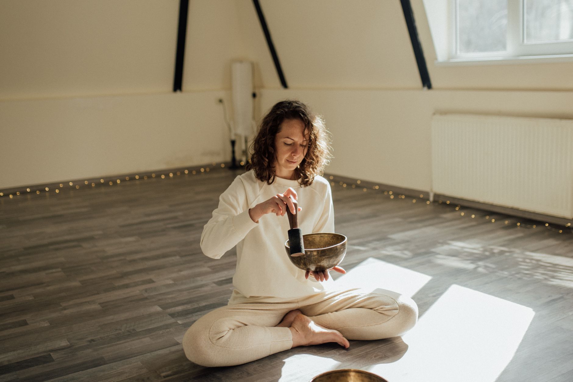 Serene woman meditating indoors with a Tibetan singing bowl, capturing tranquil vibes.