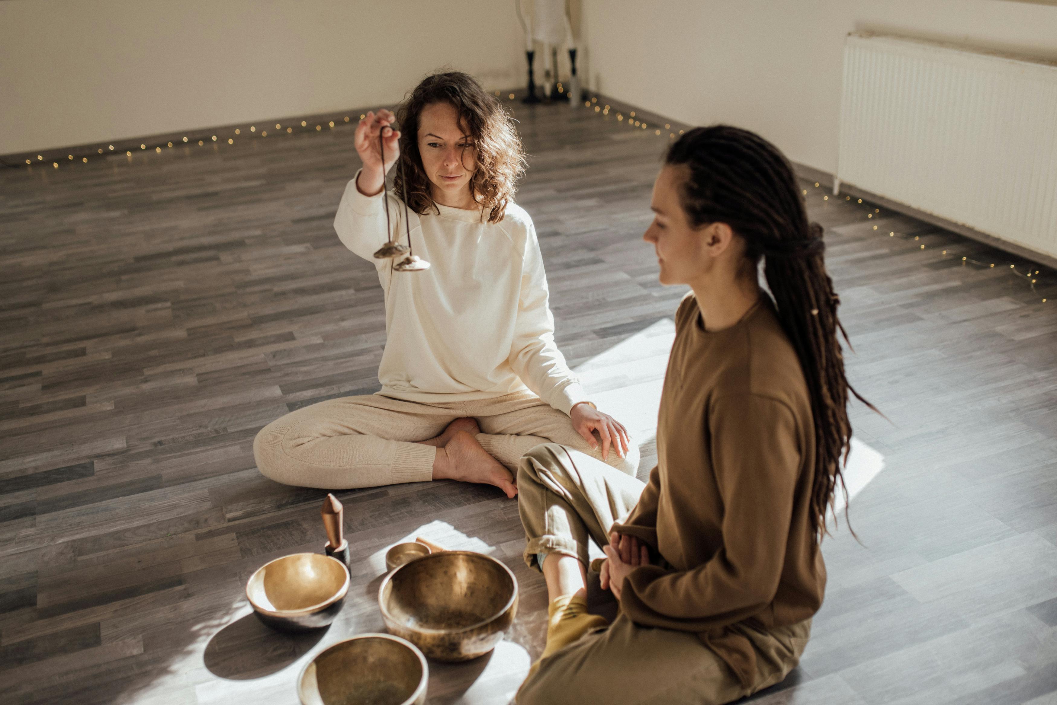 Women Meditating with Tibetan Singing Bowls while Sitting on the Floor