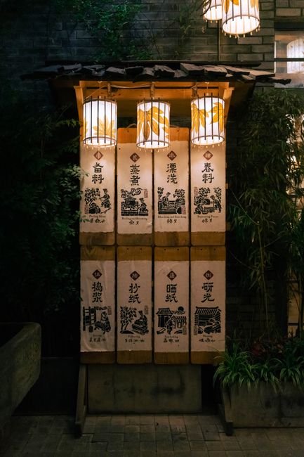 Illuminated traditional Chinese lanterns and artistic drawings outdoors at night.