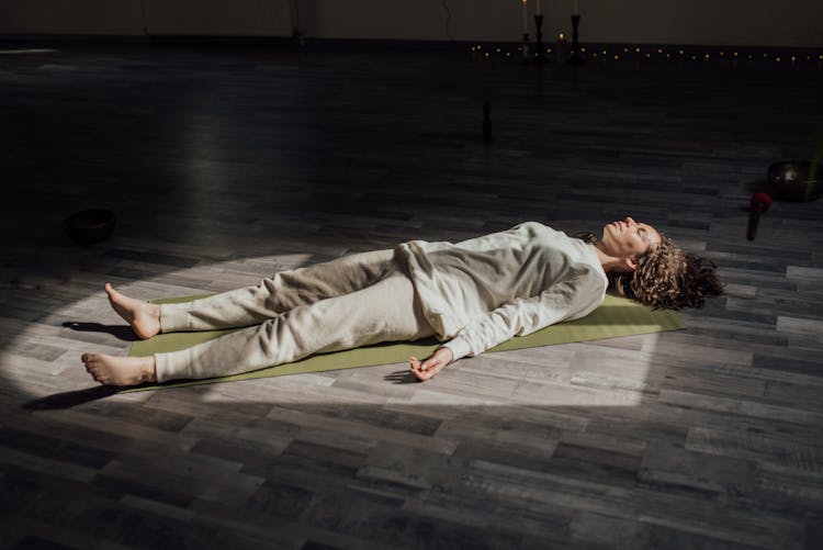 Woman Lying Down On Floor Relaxing And Meditating