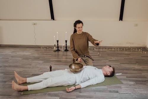 A Woman Holding a Tibetan Tingsha over a Man Lying Down