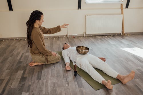 A Woman Holding a Tibetan Tingsha over a Man Lying Down