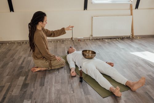 Free Two adults meditating indoors with a Tibetan singing bowl during a relaxation ritual. Stock Photo